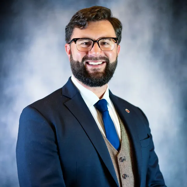 Dan Sloat, founder and president of the Advanced Air Mobility Institute, smiling in a navy suit, herringbone waistcoat and blue tie